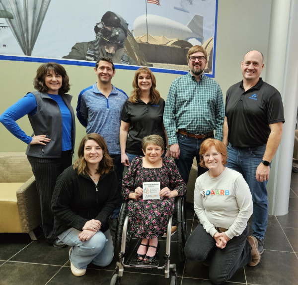 Aerostar DIP award presentation. Pictured below Back Row L-R: Anastasia Quanback, Culture and Communications Director; Travis Anderson, Senior Manager FP&A; Lisa Johnson, Human Resources Director; Russ Van Der Werff, Vice President of Stratospheric Solutions; and Jim Nelson, President. Front Row L-R: Lora Hayes, Learning and Development Manager; Vicki Stewart, Employment Disability Resources; and Cathleen Zepeda, DAARB.